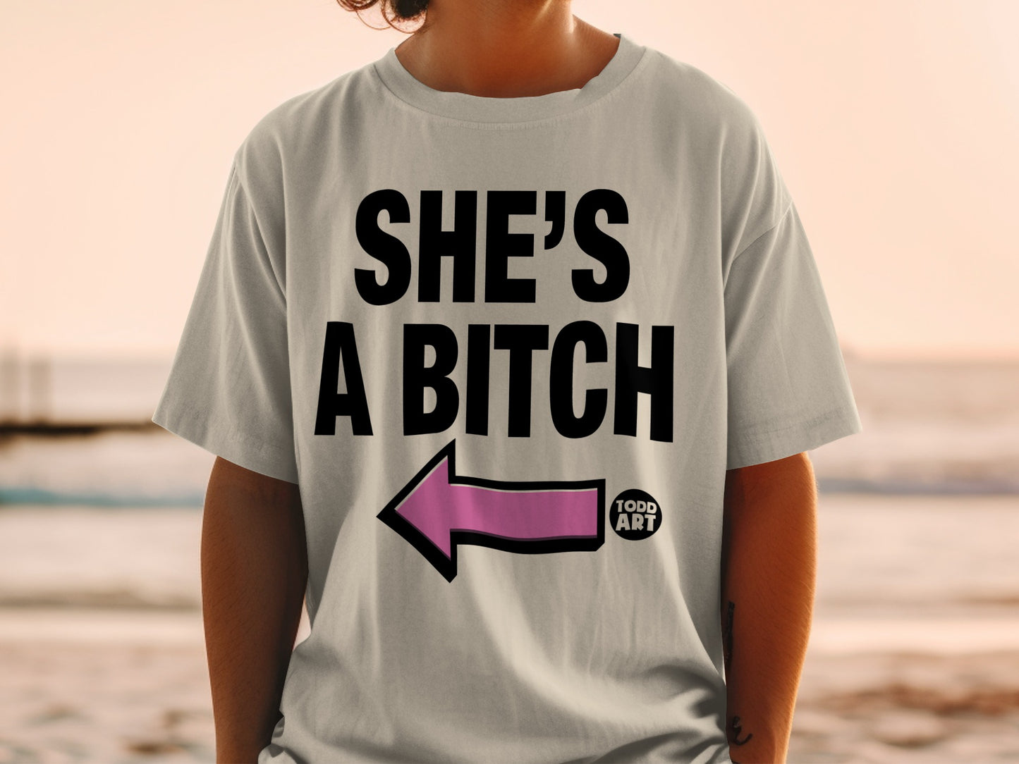 'SHE'S A BITCH' pink arrow left pointing light gray t-shirt product type
