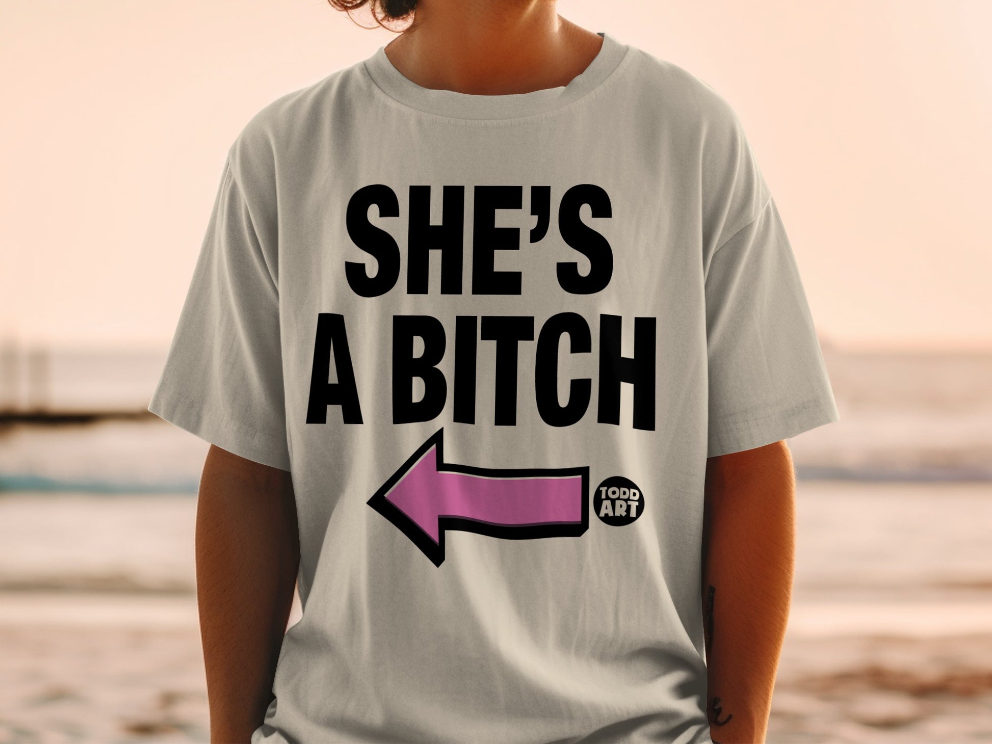 'SHE'S A BITCH' pink arrow left pointing light gray t-shirt product type