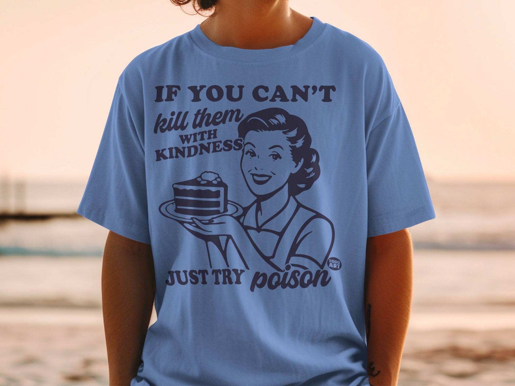 Blue t-shirt with "If you can't kill them with kindness, just try poison" text and retro woman with cake.