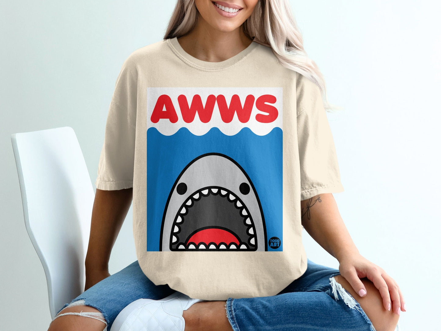 Cream t-shirt with a cartoon shark graphic and "AWWS" text.