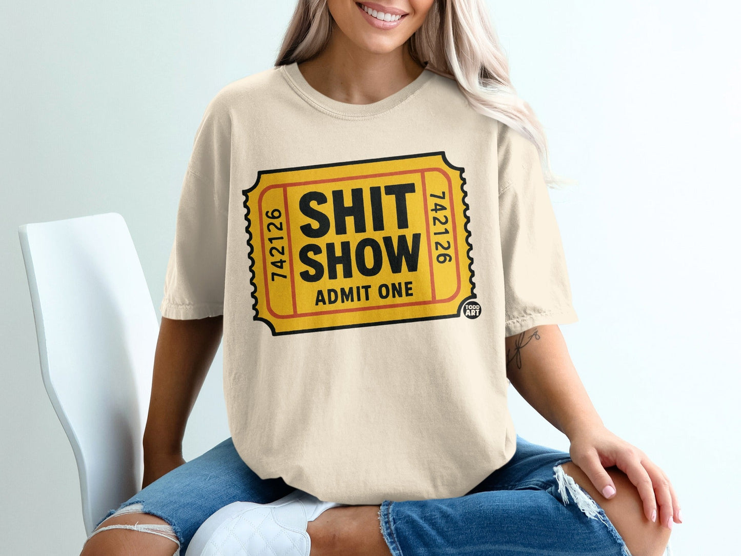 Cream t-shirt with a yellow ticket graphic saying "SHIT SHOW ADMIT ONE".