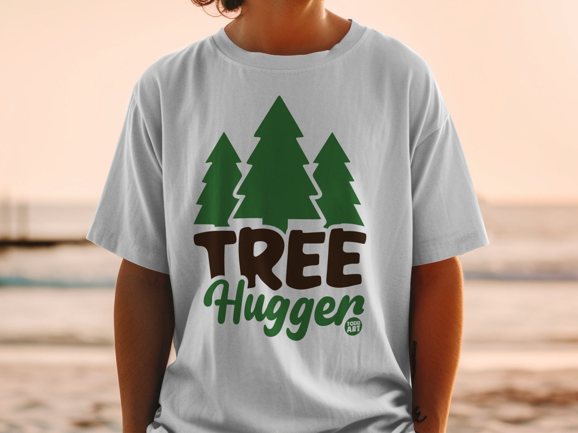 White t-shirt with green "Tree Hugger" text and three evergreen trees.