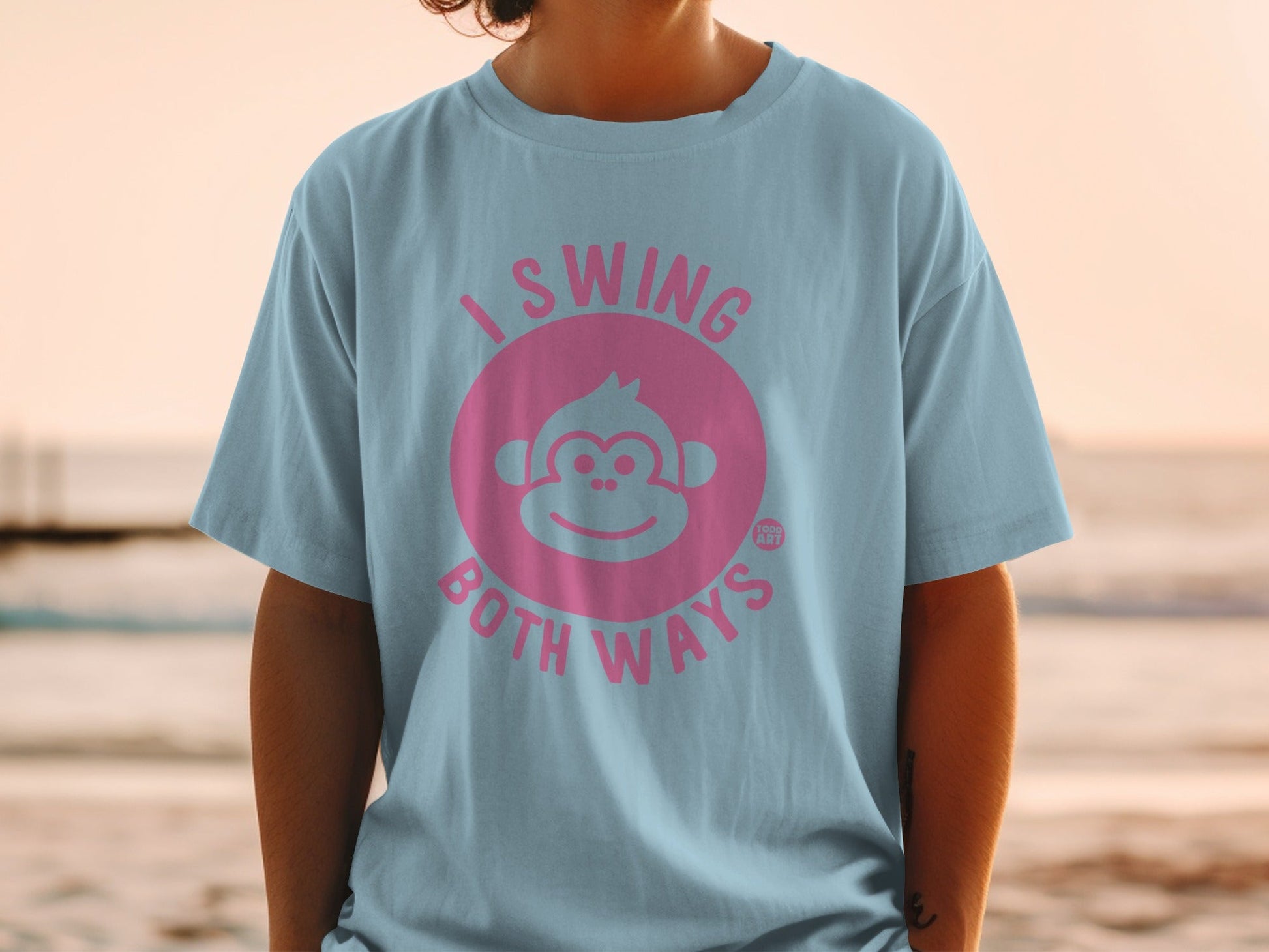 Light blue t-shirt with pink monkey graphic and "I SWING BOTH WAYS" text.