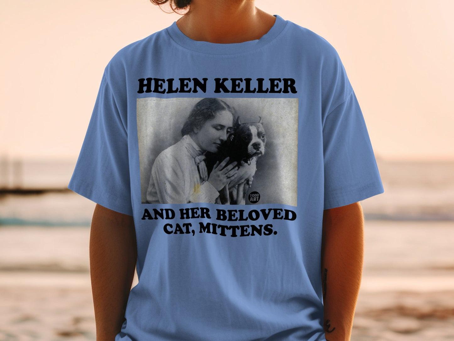 Blue t-shirt with "HELEN KELLER AND HER BELOVED MITTENS" text and a photo.