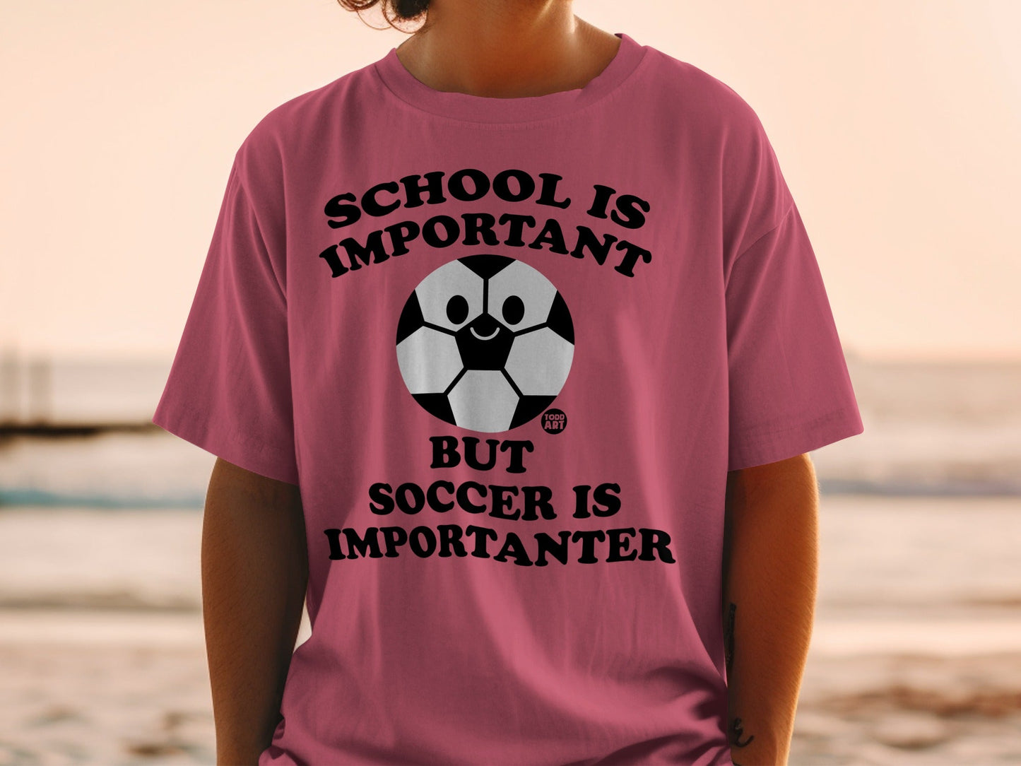 Pink t-shirt with "SCHOOL IS IMPORTANT BUT SOCCER IS IMPORTANTER" text and a soccer ball graphic.