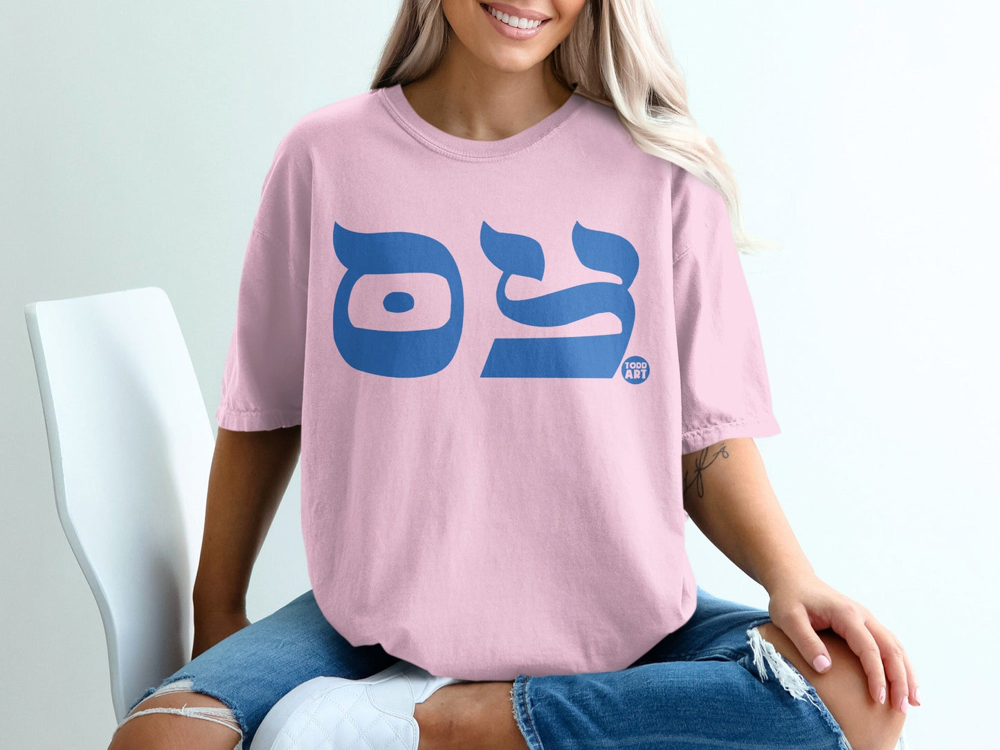 Pink t-shirt with blue Hebrew letters and a small "TODD ART" logo.