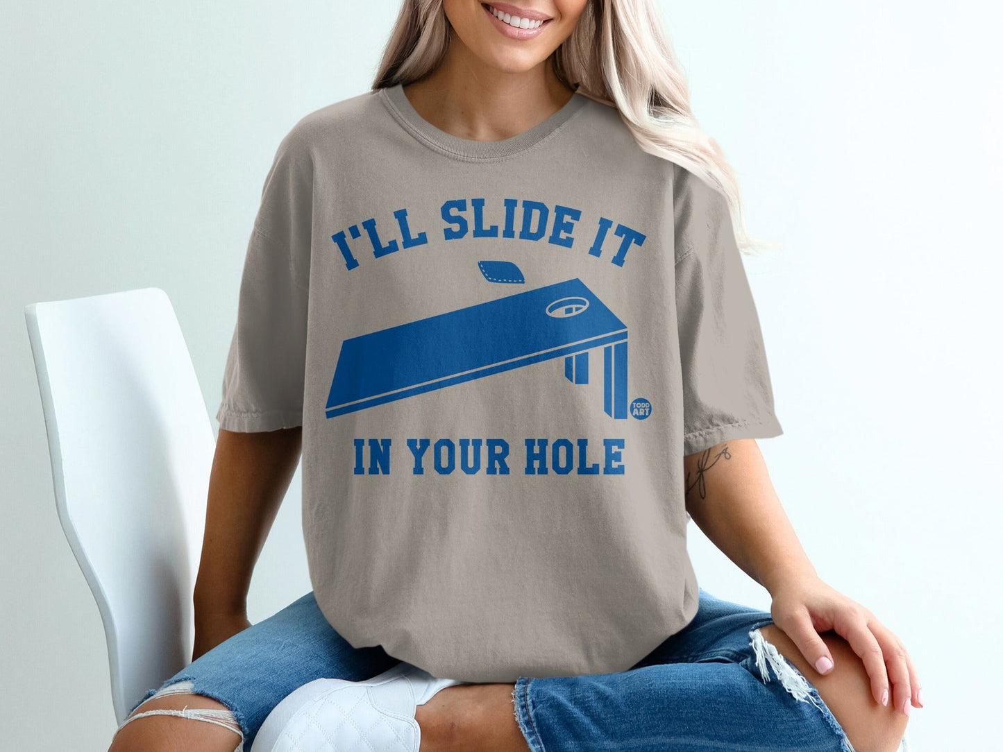Tan t-shirt with "I'll slide it in your hole" and cornhole board graphic.