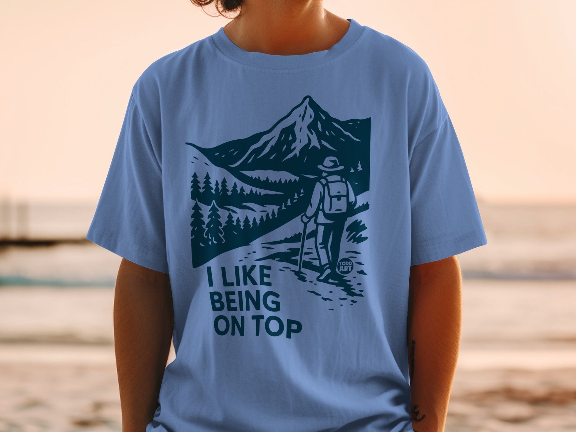 Light blue t-shirt with "I LIKE BEING ON TOP" mountain hiking graphic.