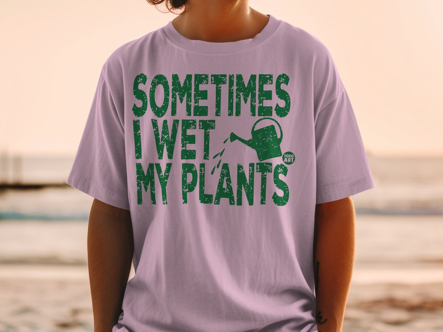 Light purple t-shirt with green text "SOMETIMES I WET MY PLANTS" and a watering can.