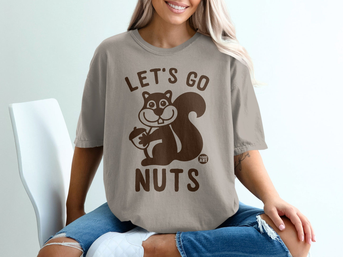 Brown t-shirt with cartoon squirrel holding acorn, text "LET'S GO NUTS".