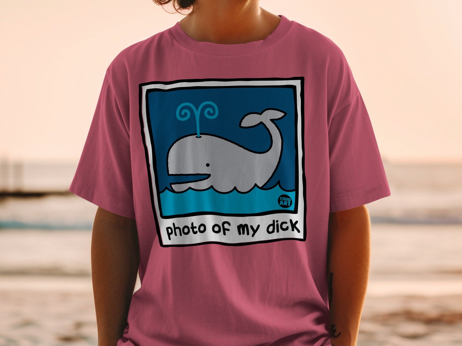 Pink t-shirt with a blue cartoon whale illustration and "photo of my dick" text.