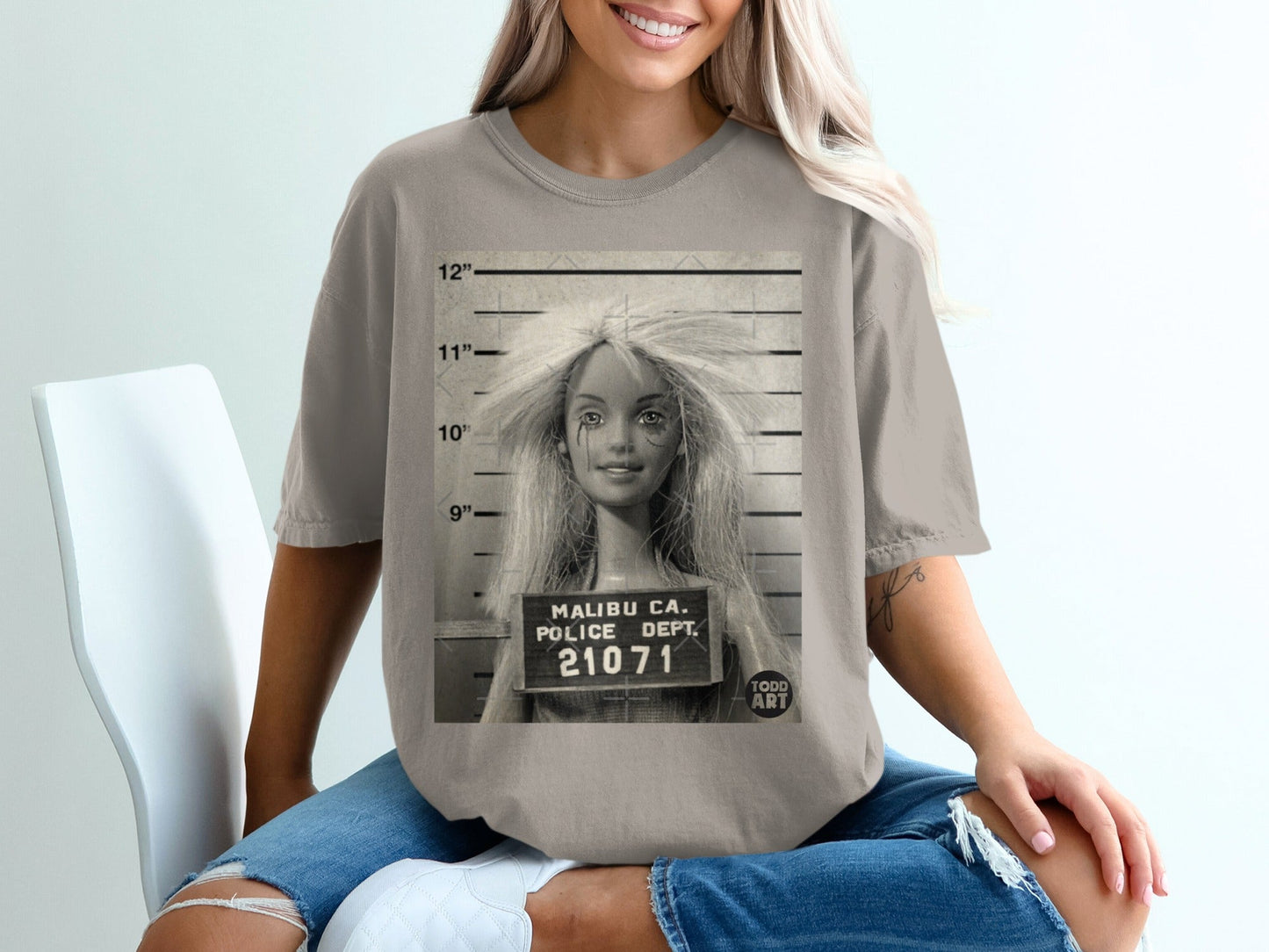 Mugshot of a doll with "Malibu Ca. Police Dept. 21071" on a placard.