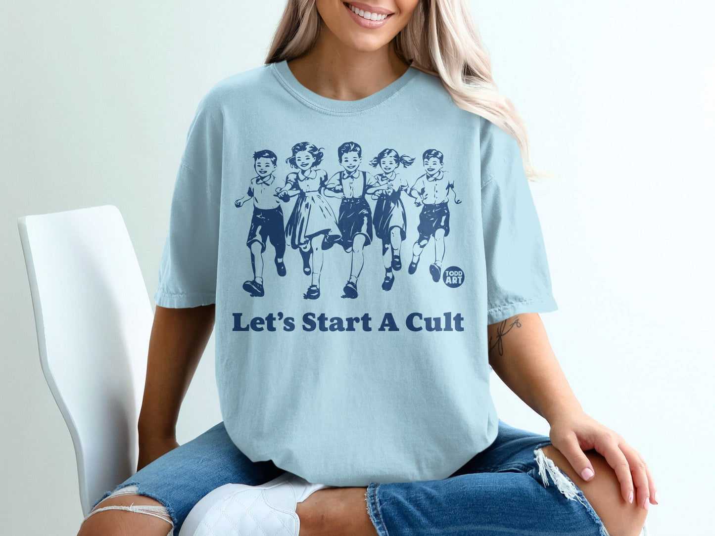 Light blue t-shirt with graphic of children running and "Let's Start A Cult" text.