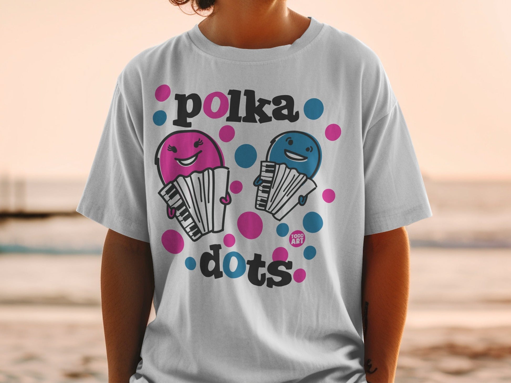 Two cartoon accordions with smiling faces on a white polka dot t-shirt.