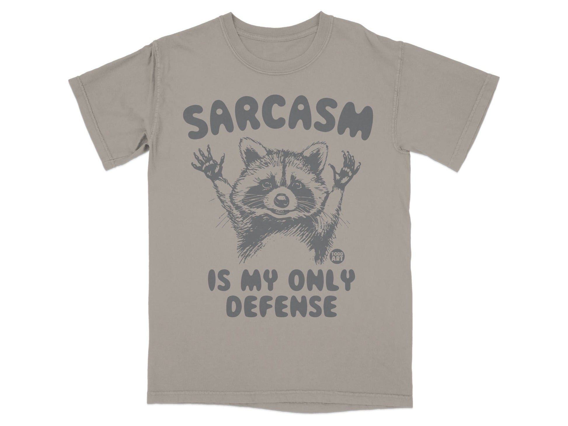 Gray t-shirt with raccoon graphic and text "SARCASM IS MY ONLY DEFENSE".