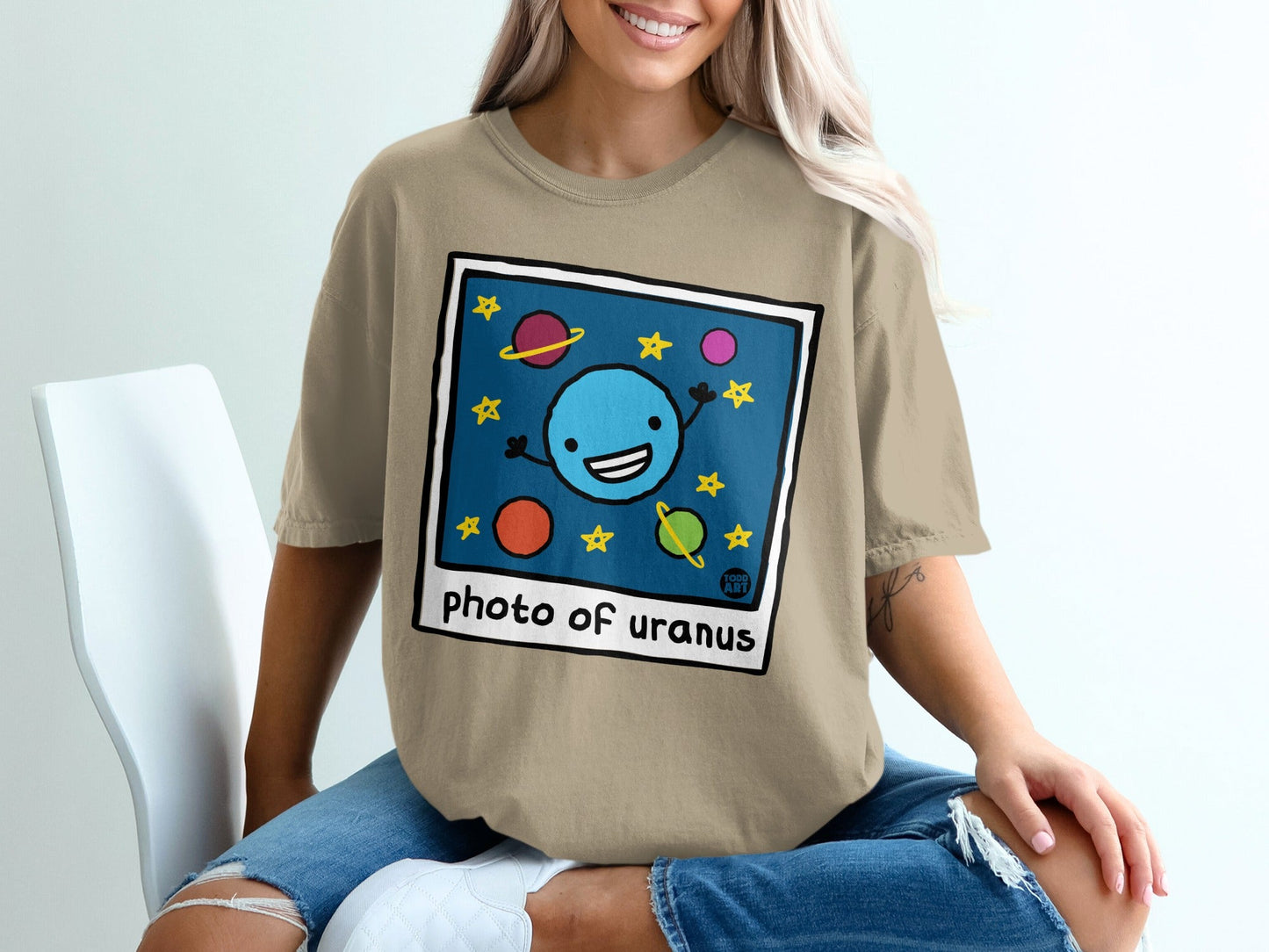 T-shirt with a cartoon drawing of a happy planet named Uranus, stars, and other planets.