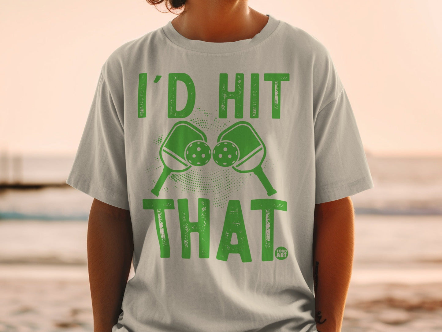 Green t-shirt with pickleball paddles and balls, "I'd Hit That" text.