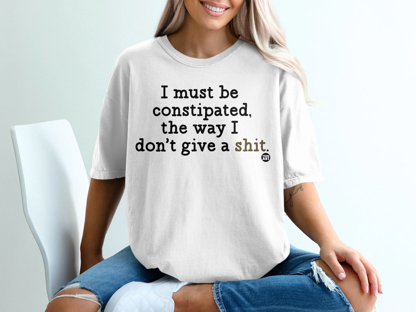 White t-shirt with "I must be constipated, the way I don't give a shit" text.
