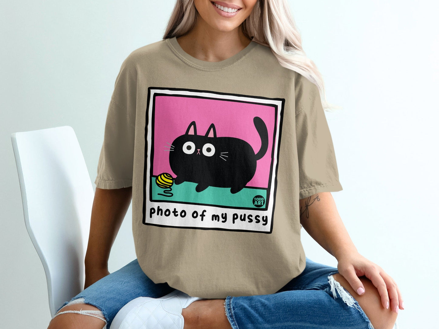 Tan t-shirt with a framed cartoon black cat and yellow yarn.