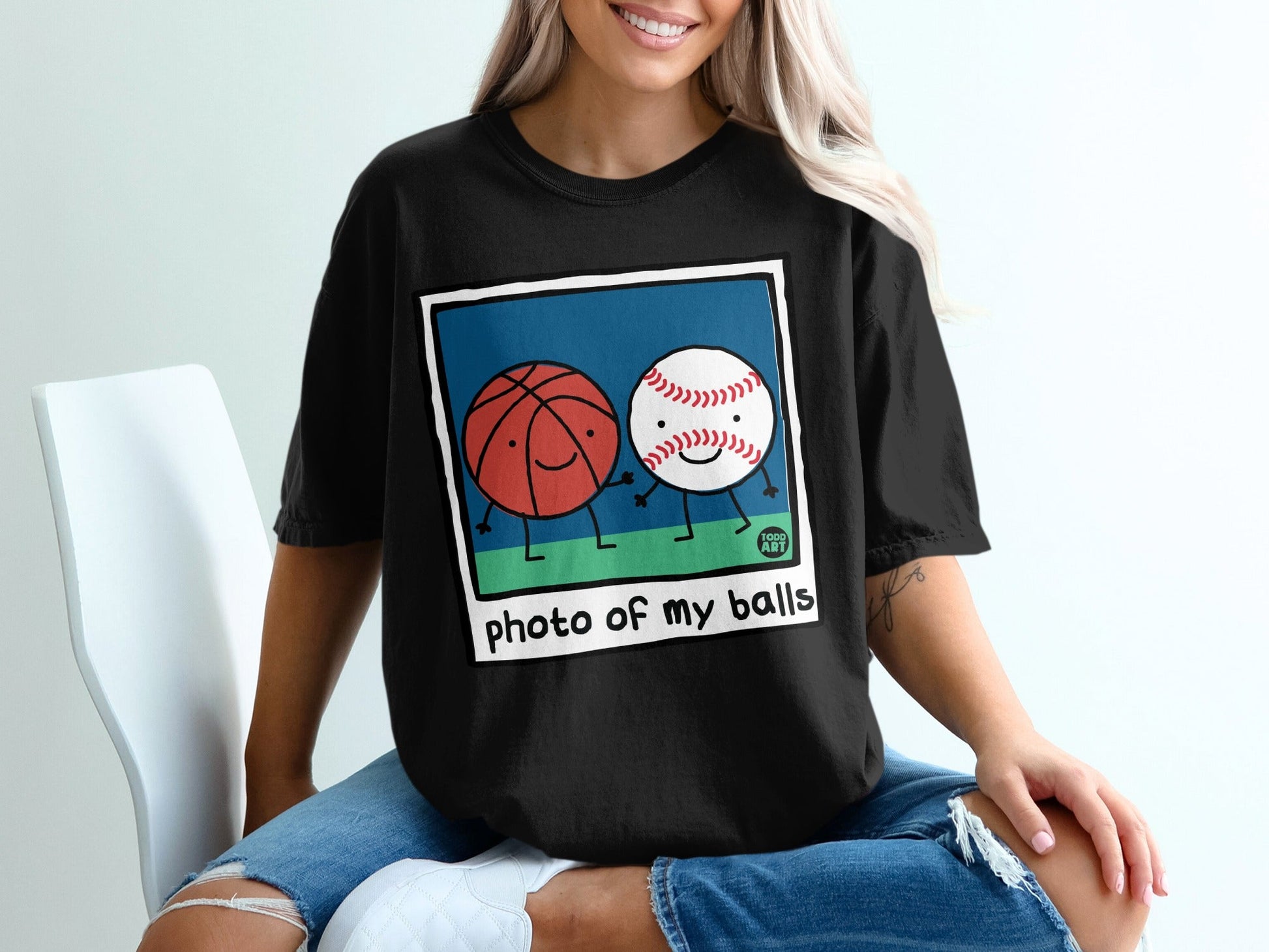 Black t-shirt with cartoon basketball and baseball holding hands.