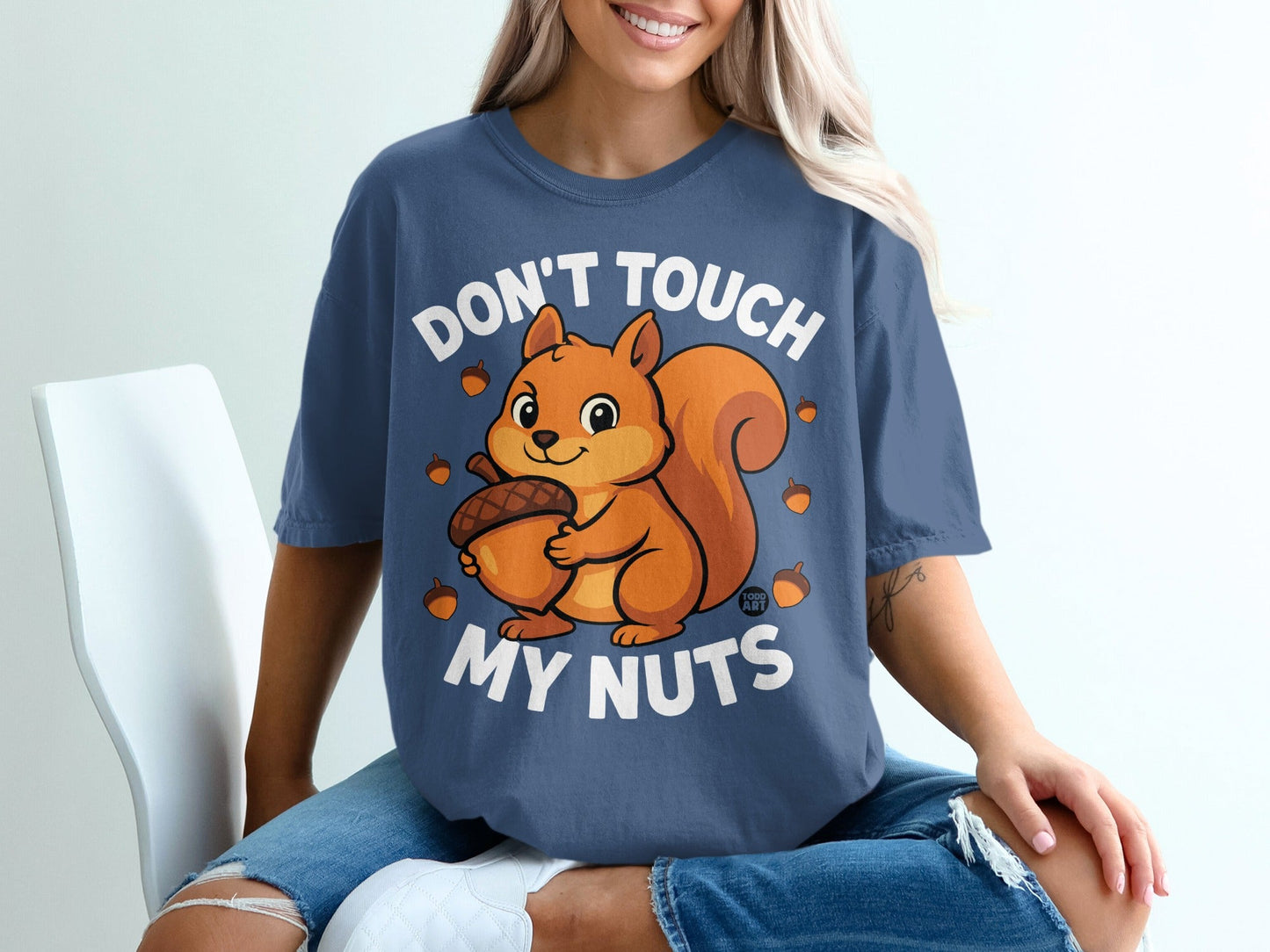 Blue t-shirt with a cartoon squirrel holding an acorn and text "DON'T TOUCH MY NUTS".