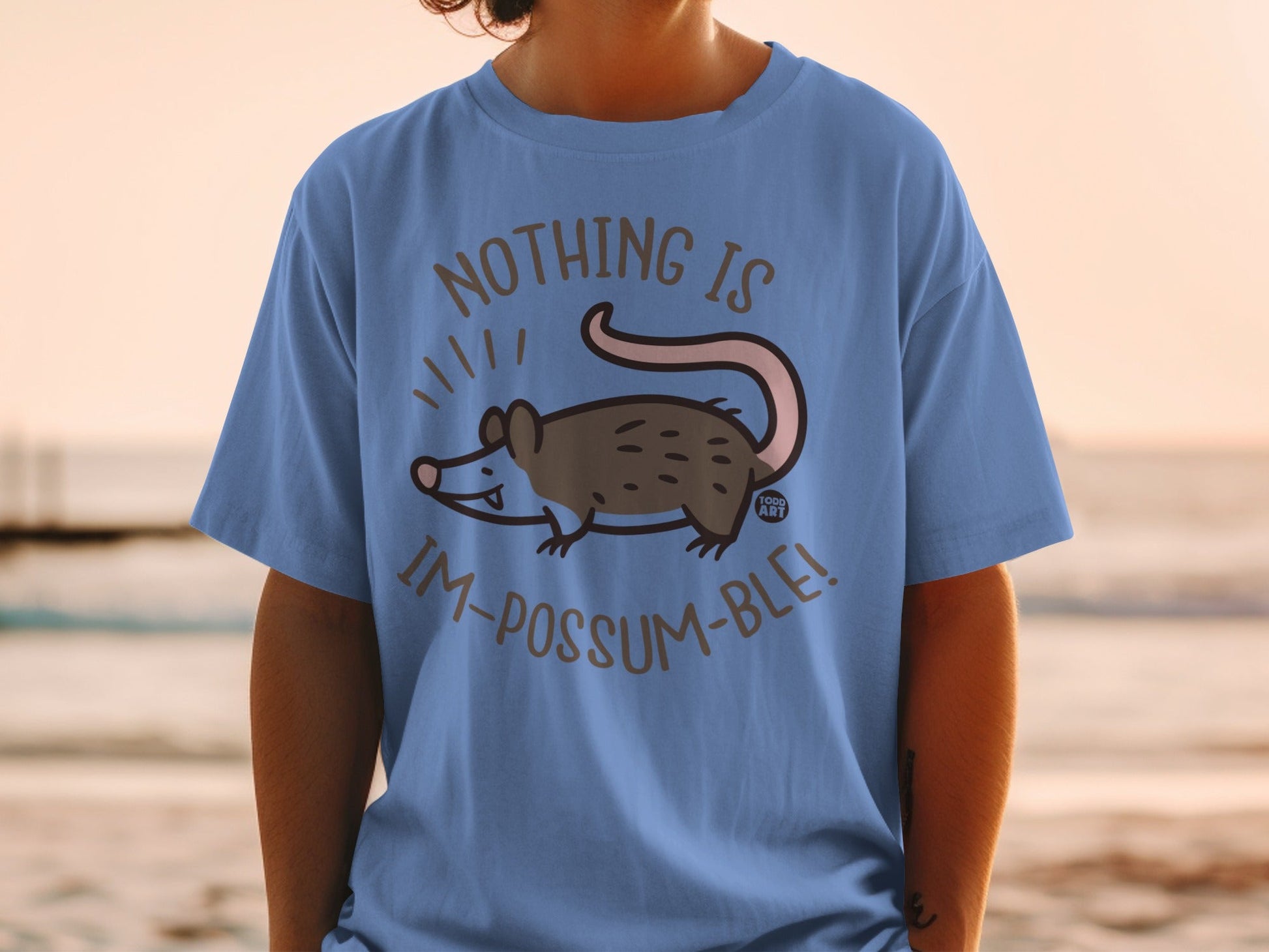 Blue t-shirt with a cartoon possum and text: Nothing is Im-possum-ble!