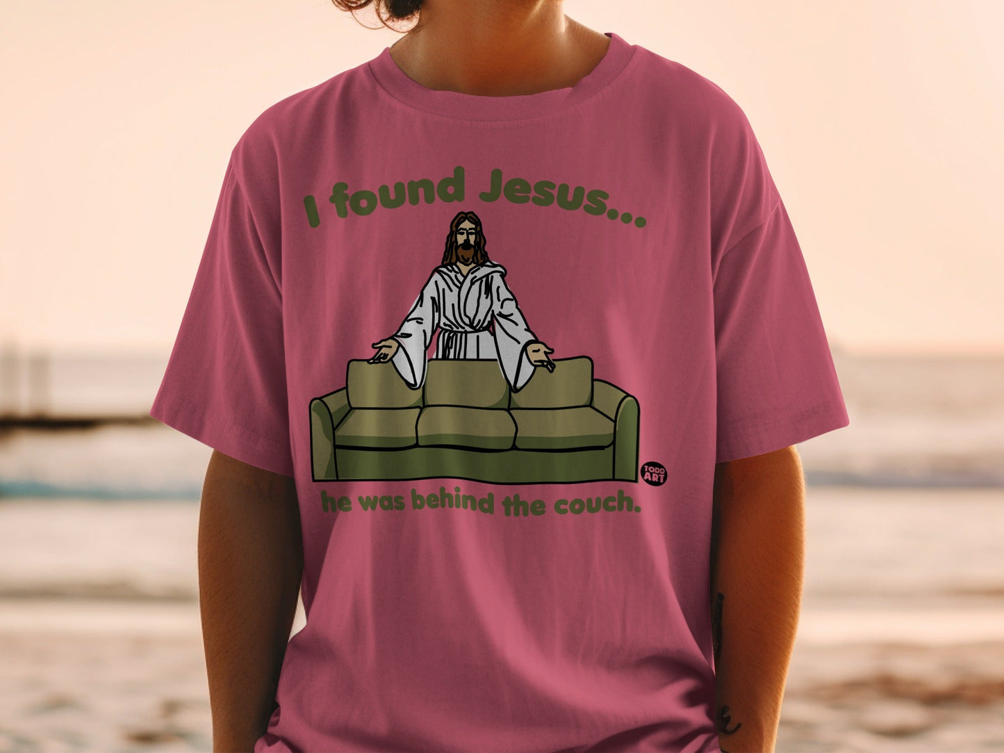 T-shirt with "I found Jesus... he was behind the couch." text and Jesus on a couch graphic.