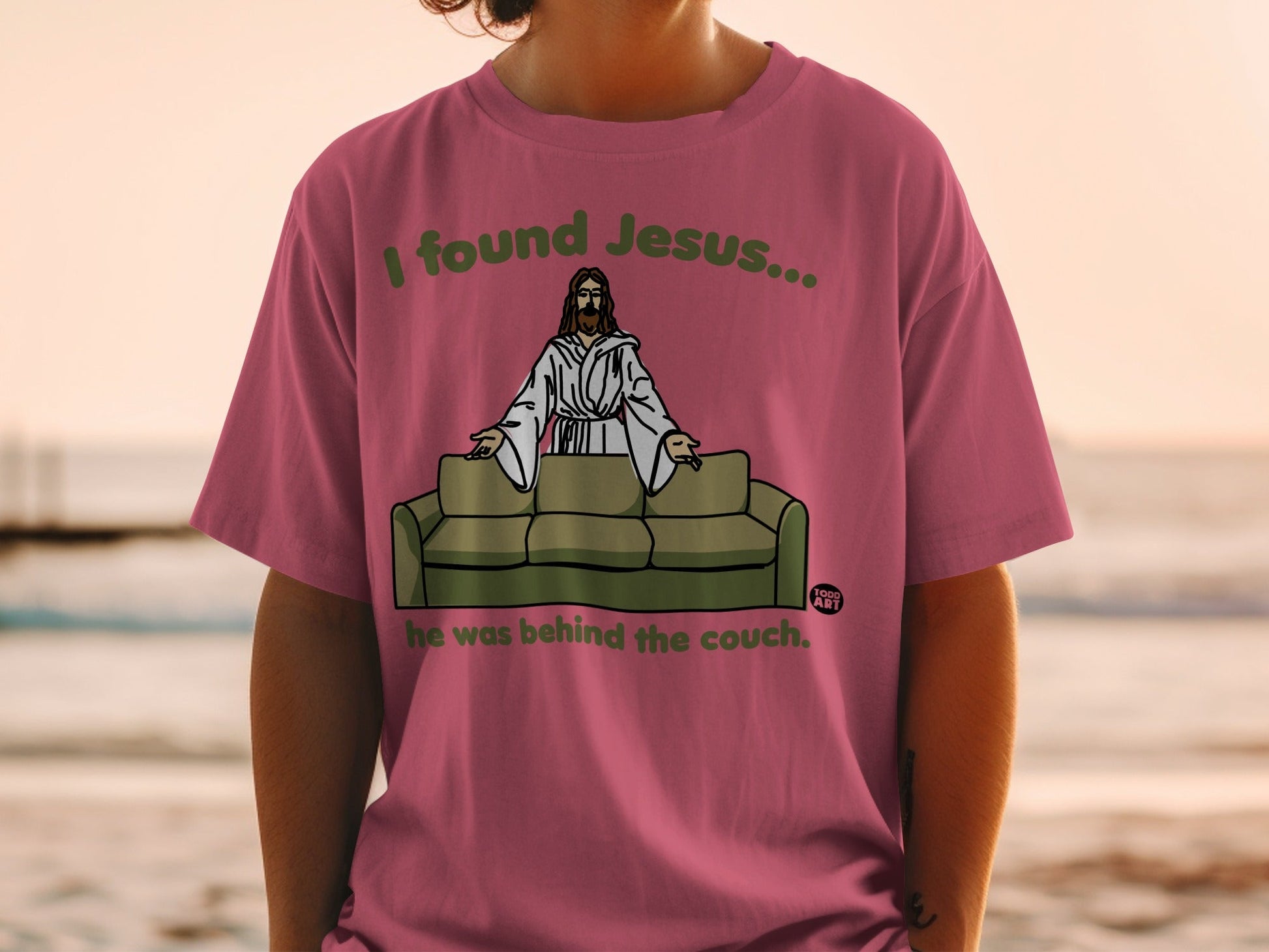 T-shirt with "I found Jesus... he was behind the couch." text and Jesus on a couch graphic.
