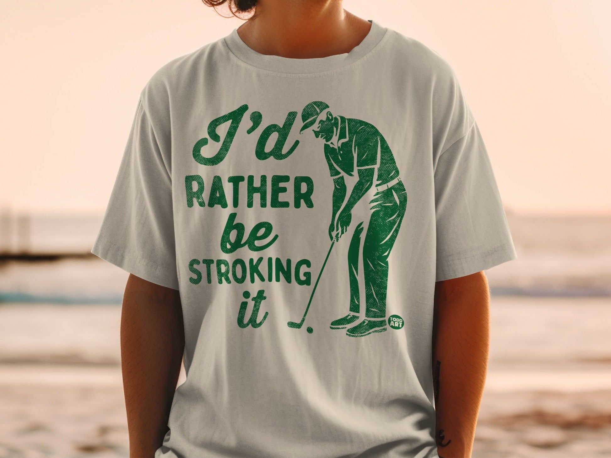 Green t-shirt with graphic of golfer and text "I'd rather be stroking it".