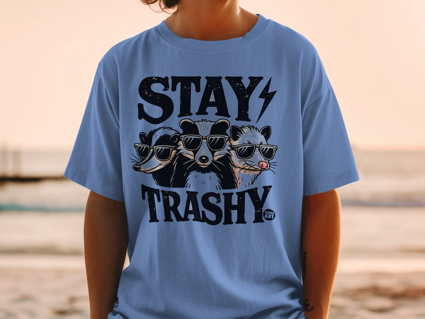 T-shirt with "STAY TRASHY" and three raccoons wearing sunglasses.