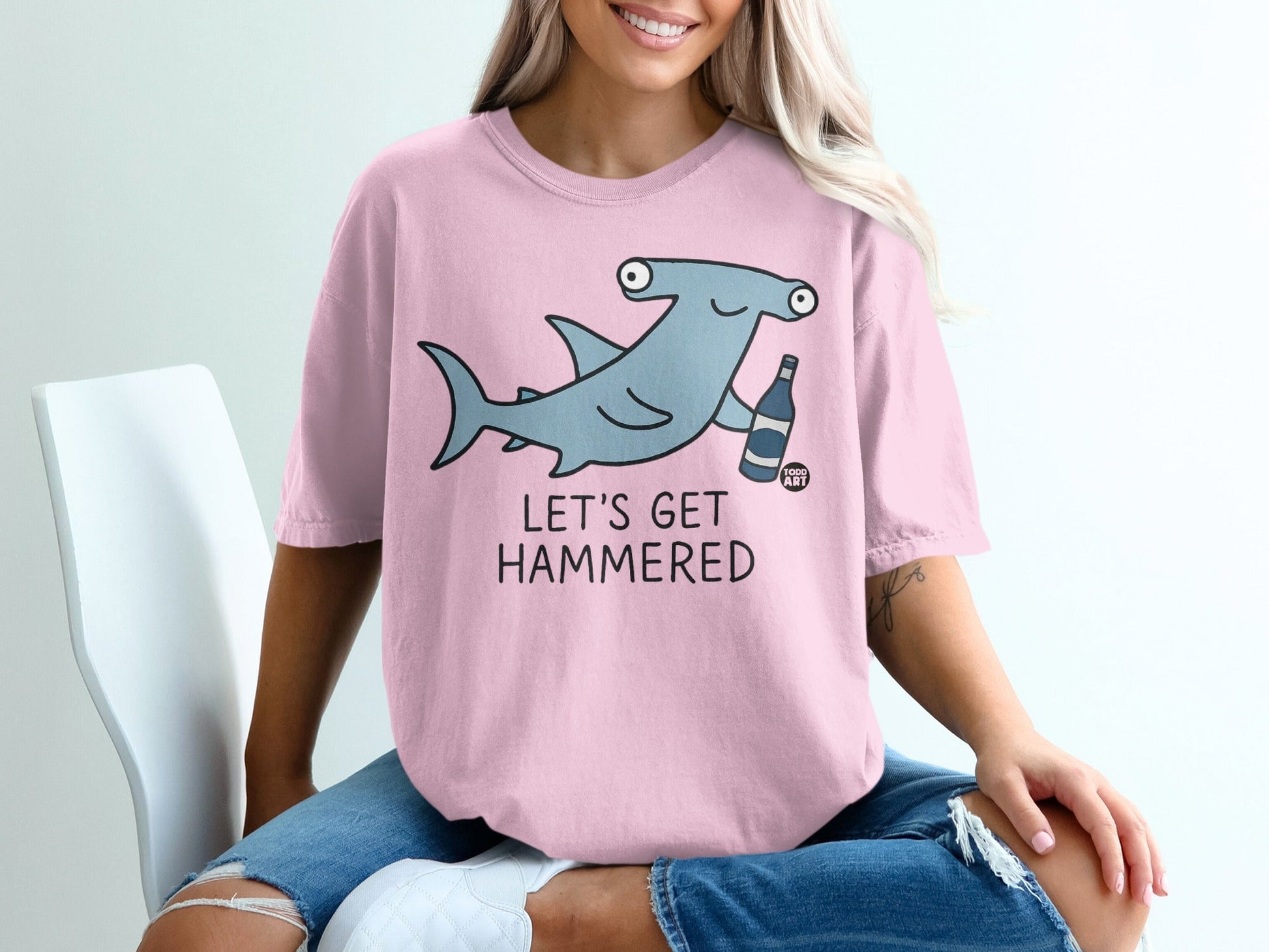 Pink t-shirt with cartoon hammerhead shark and text "LET'S GET HAMMERED."