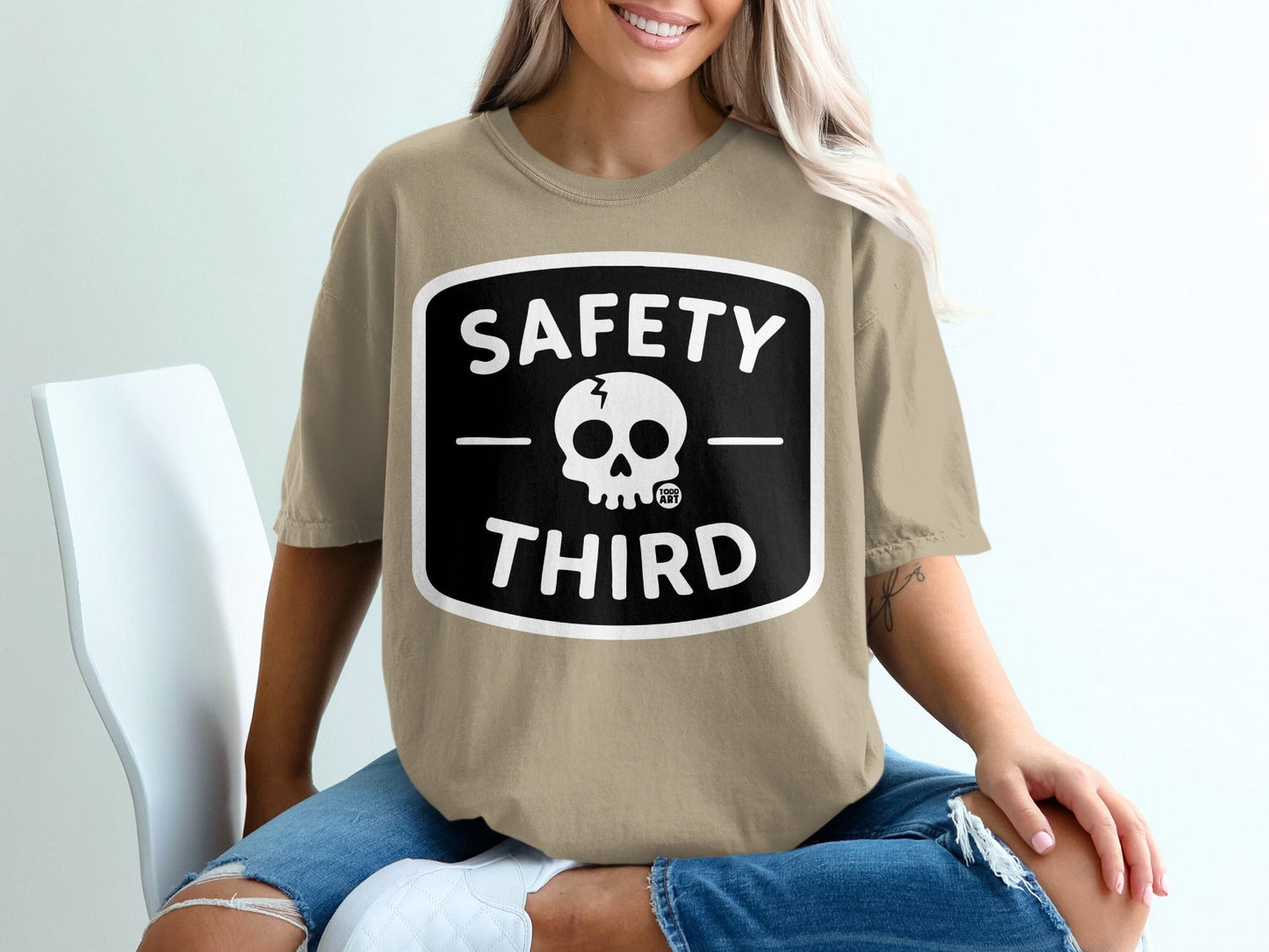 Tan t-shirt with a black square design featuring a skull and "SAFETY THIRD".