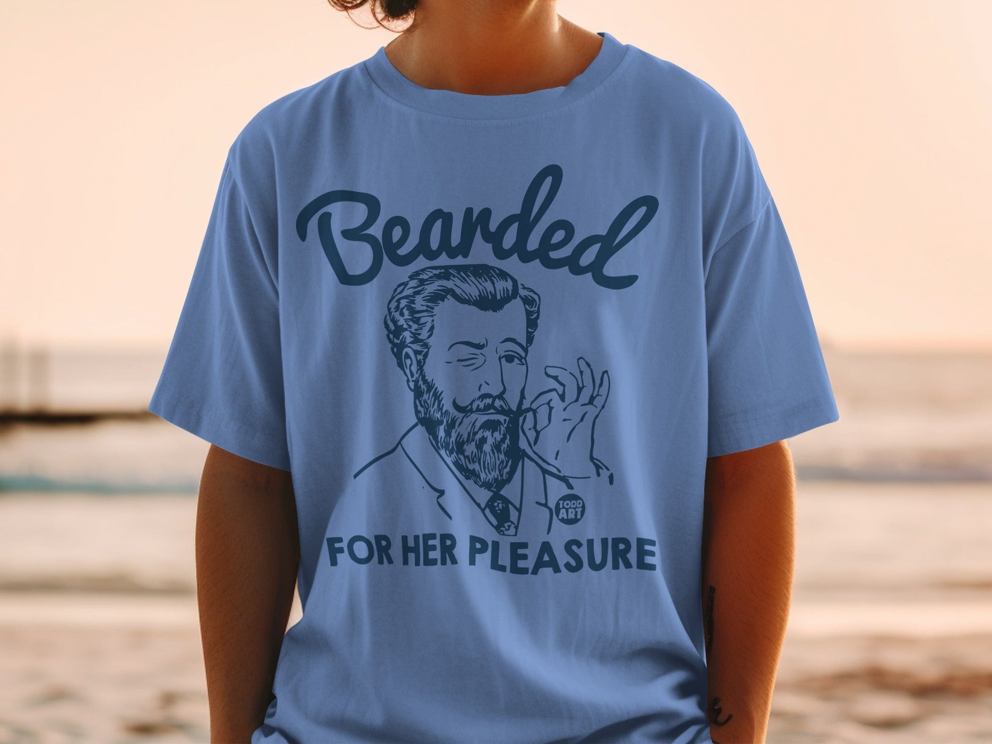 Blue t-shirt with "Bearded for her pleasure" text and illustration.