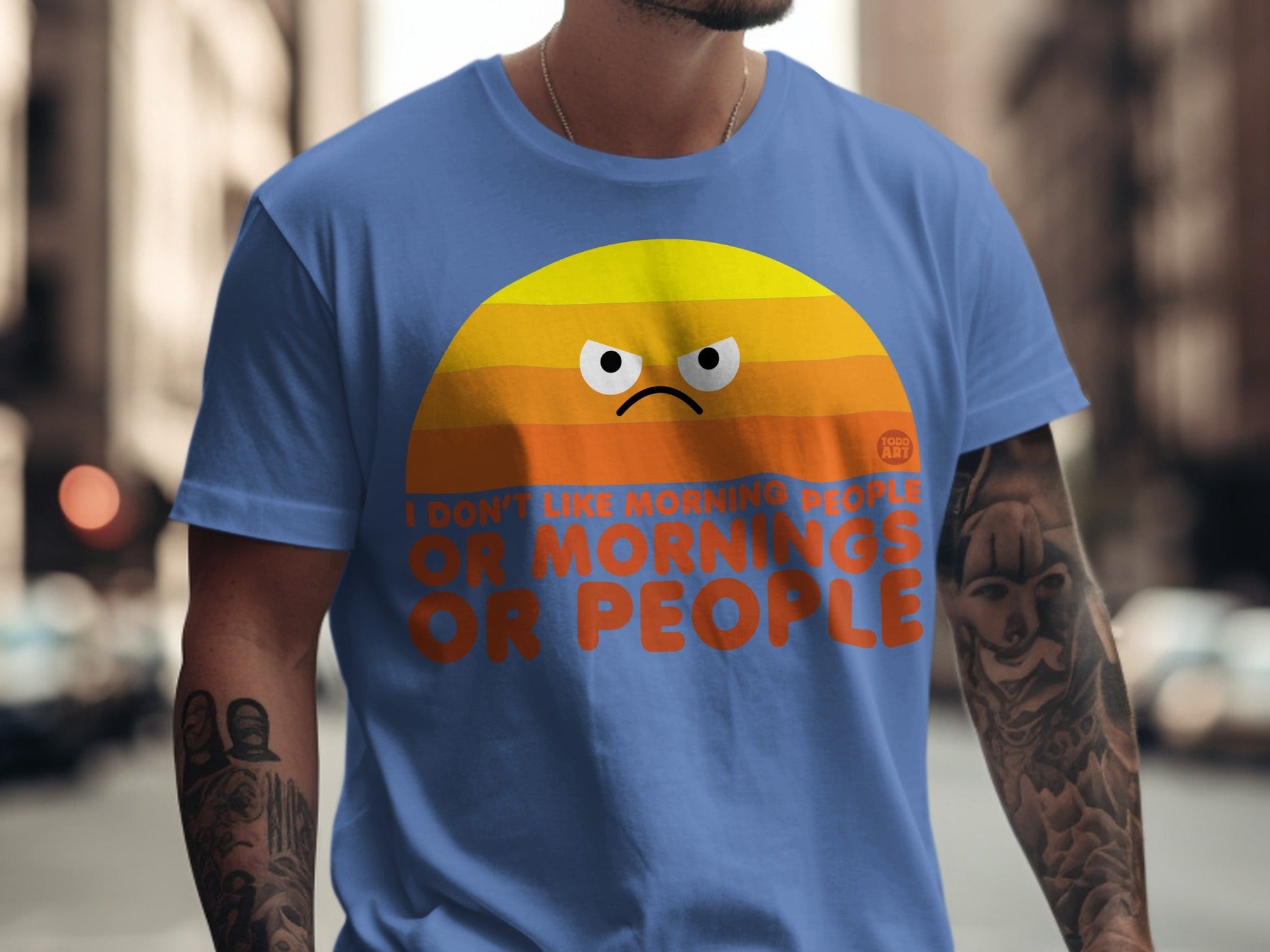 Blue t-shirt with orange sunrise graphic and "I DON'T LIKE MORNING PEOPLE OR PEOPLE" text.