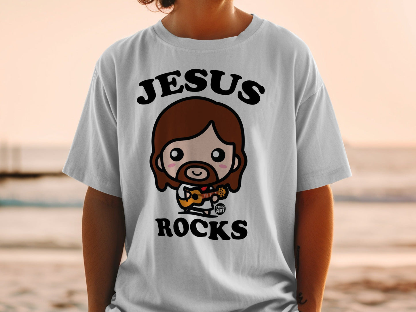 Cartoon Jesus with guitar on t-shirt, "JESUS ROCKS" text above.