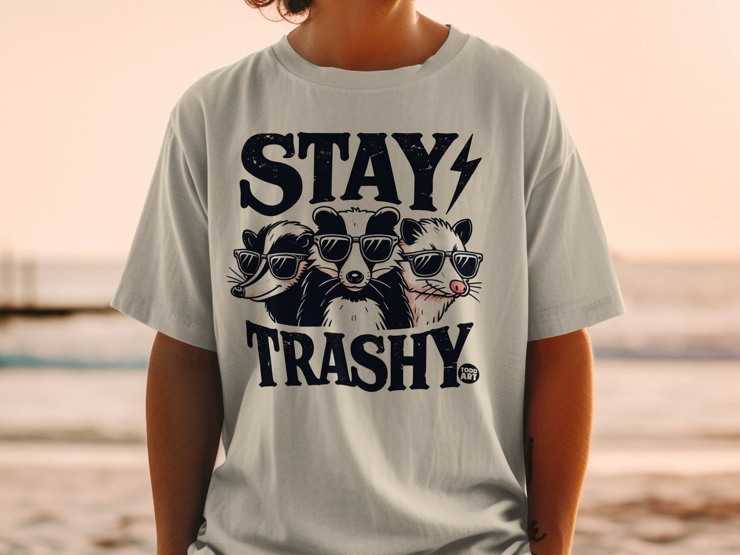 T-shirt graphic with raccoons and opossum wearing sunglasses, text "STAY TRASHY".