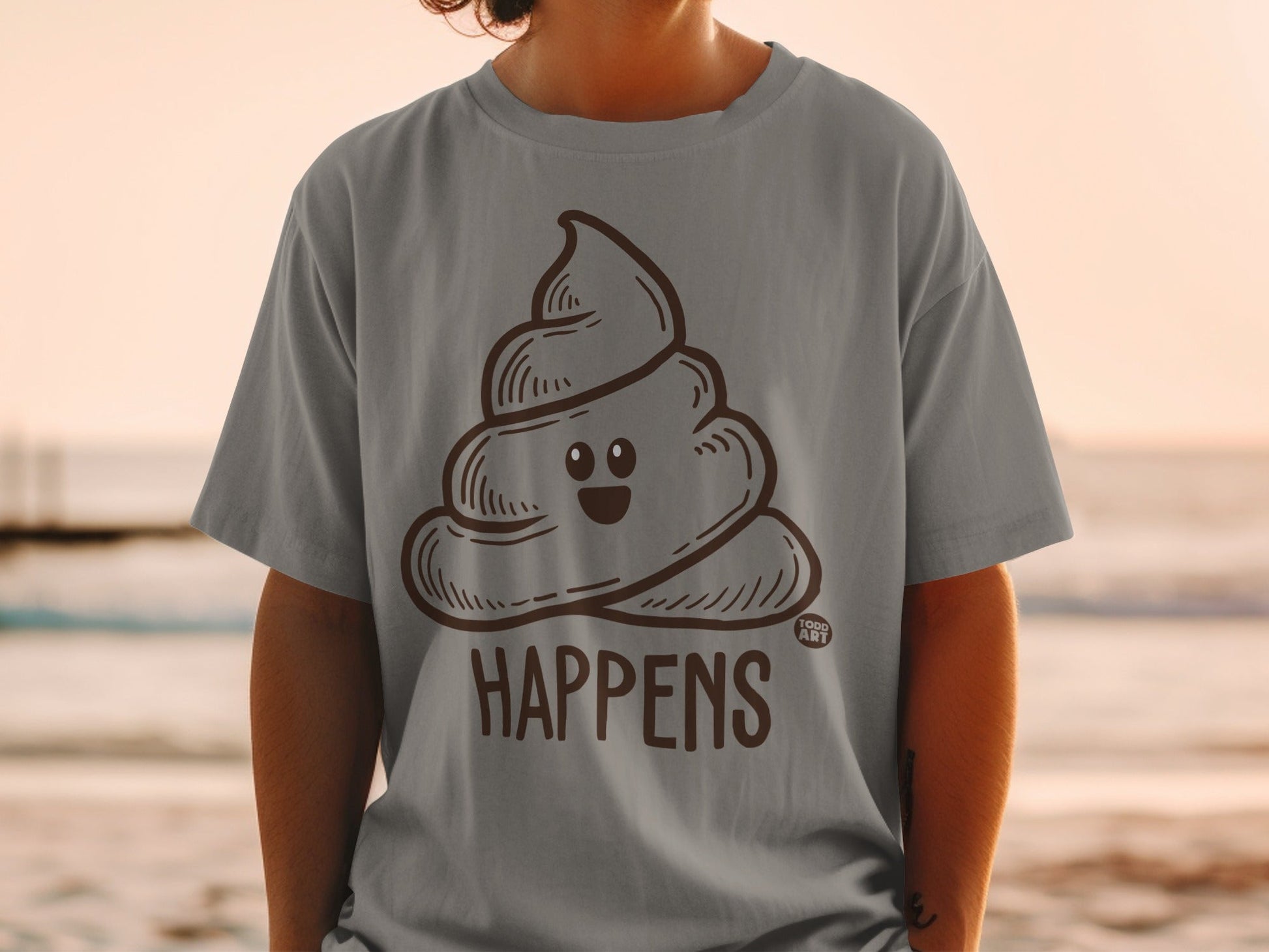 Brown cartoon poop emoji on gray t-shirt with "HA PPENS" text.