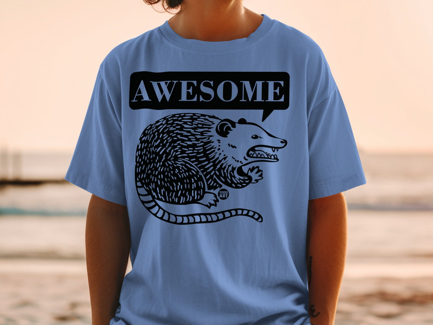 Blue t-shirt with a black graphic of an opossum and "AWESOME" speech bubble.