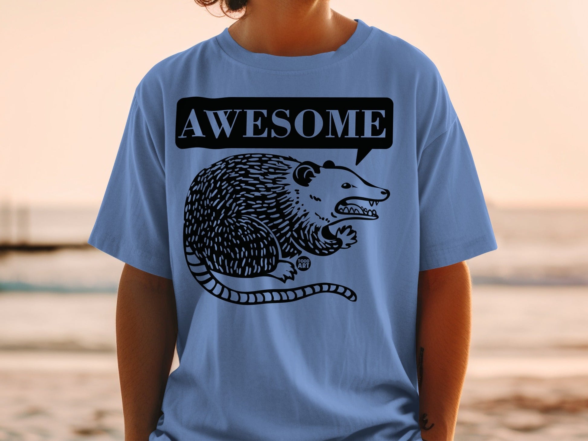 Blue t-shirt with a black graphic of an opossum and "AWESOME" speech bubble.
