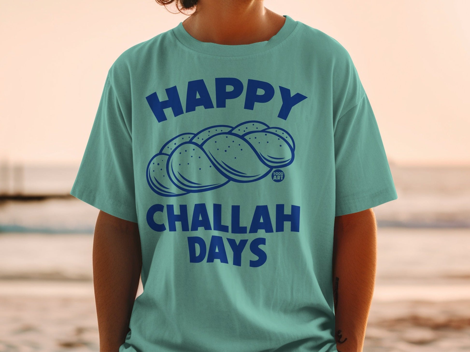 Teal t-shirt with "Happy Challah Days" and braided challah loaf graphic.