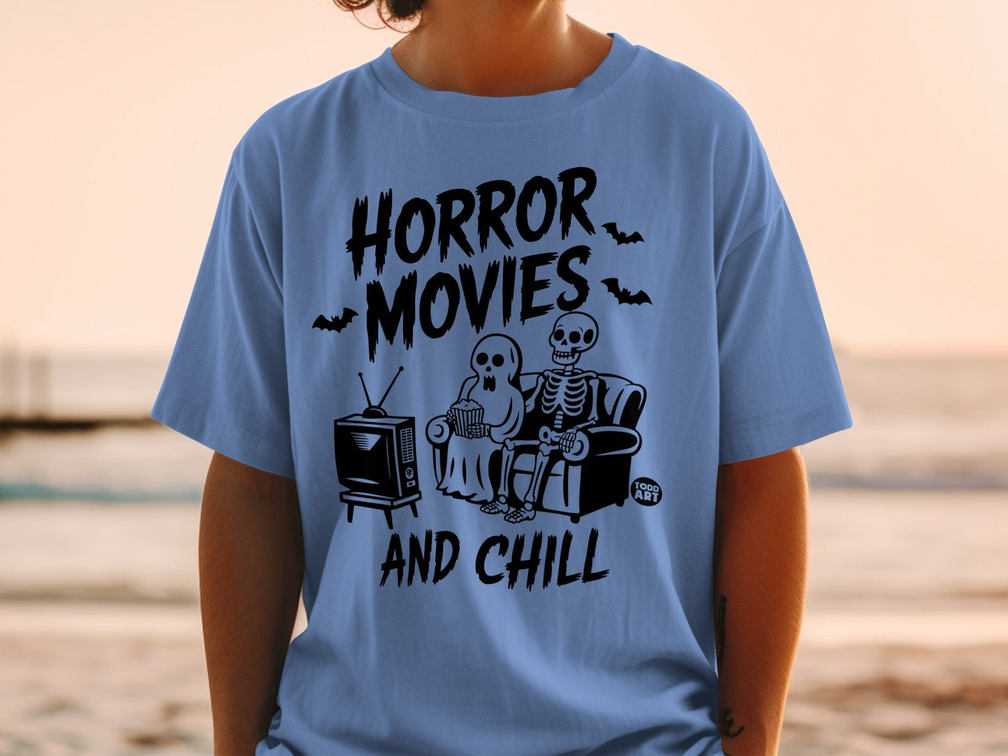 Blue t-shirt with "Horror Movies And Chill" text, skeletons, and a TV.