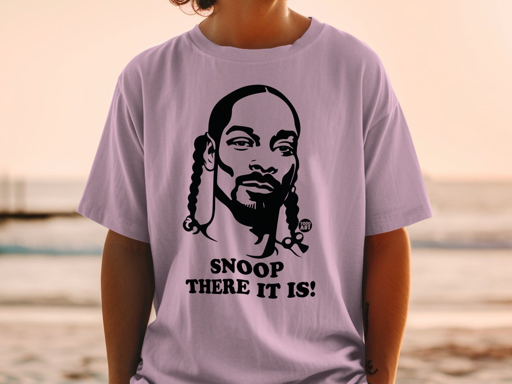 Snoop Dogg portrait on a light purple t-shirt with "SNOOP THERE IT IS!" text.