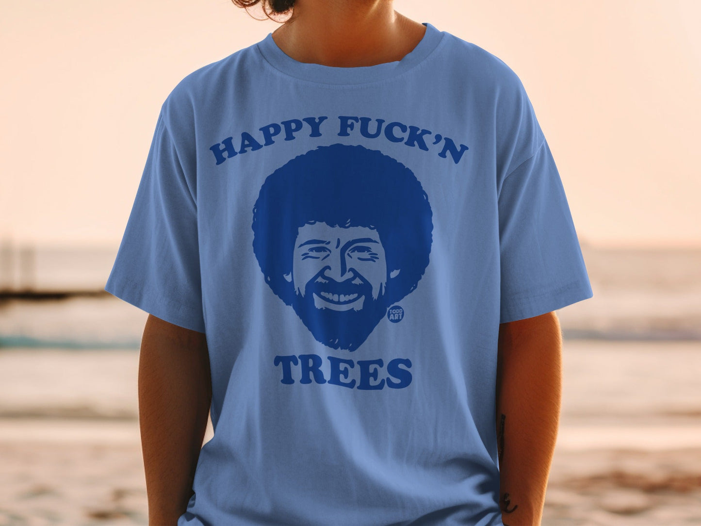 Blue t-shirt with Bob Ross graphic and text "Happy Fuck'n Trees".