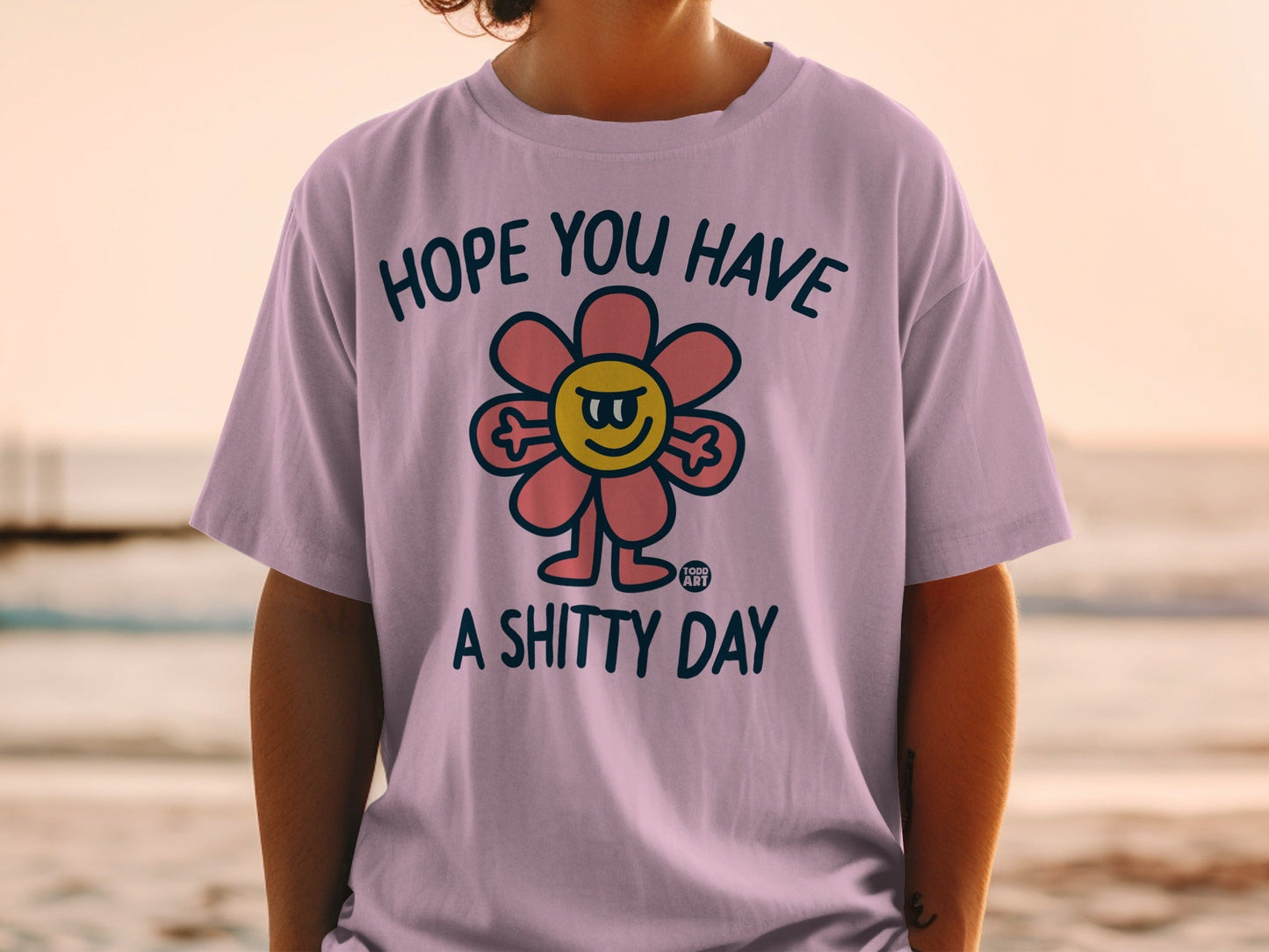 Purple t-shirt with a smiling, grumpy flower graphic and text "HOPE YOU HAVE A SHITTY DAY".