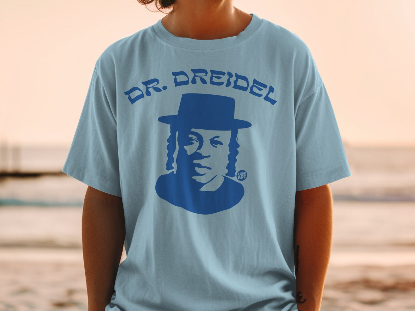 Blue graphic t-shirt with blue silhouette of a man in a hat, text "DR. DREIDEL" and "YOO ART".