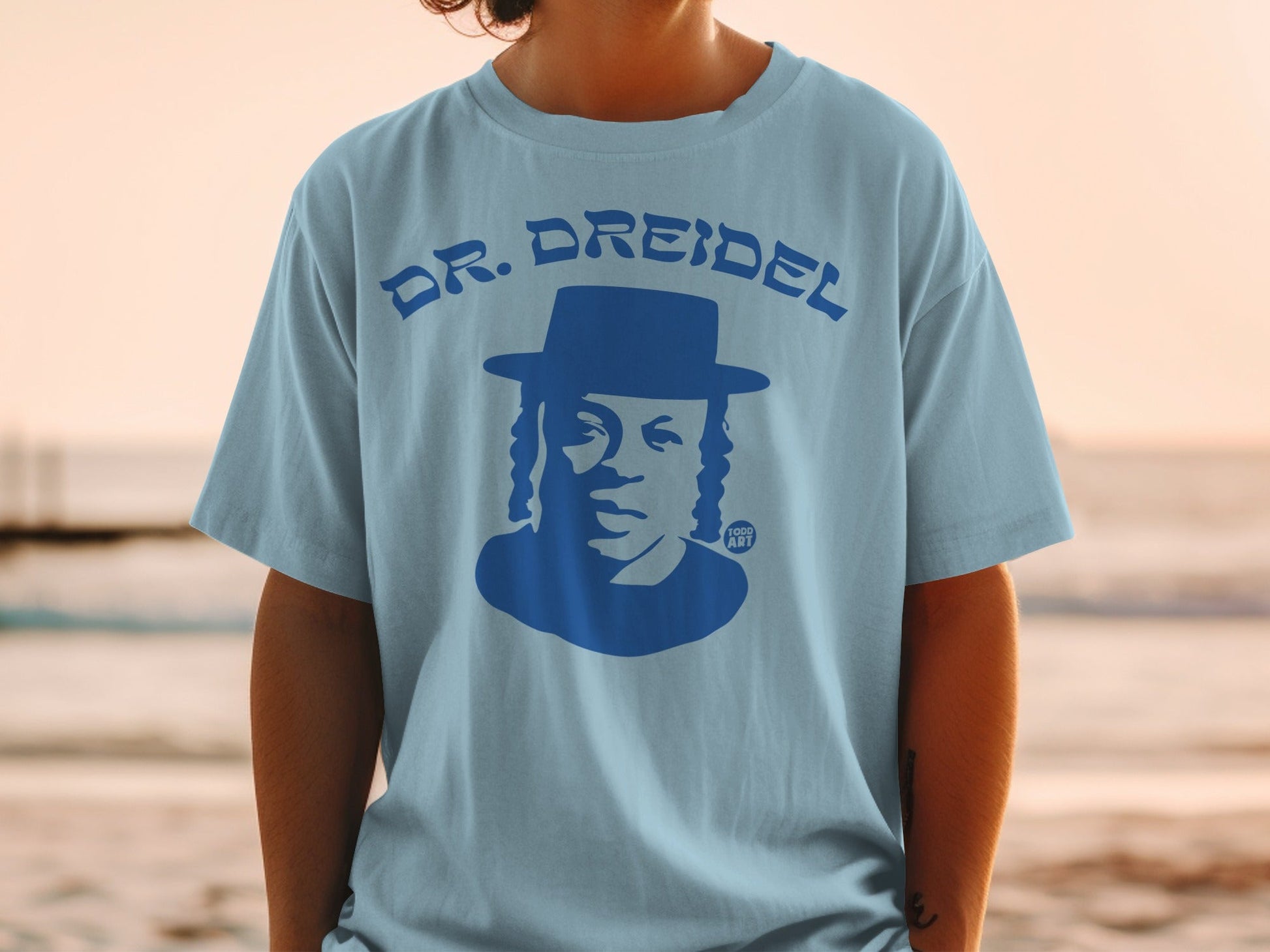 Blue graphic t-shirt with blue silhouette of a man in a hat, text "DR. DREIDEL" and "YOO ART".