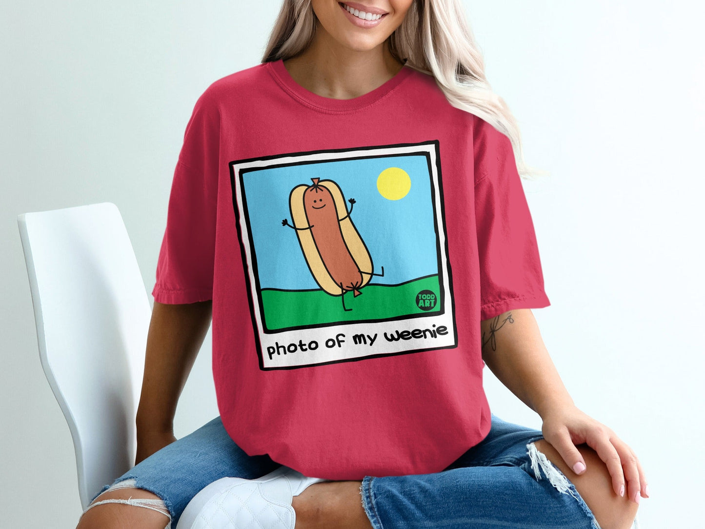 Red t-shirt featuring a cartoon hot dog with arms and legs, "photo of my weenie" text.