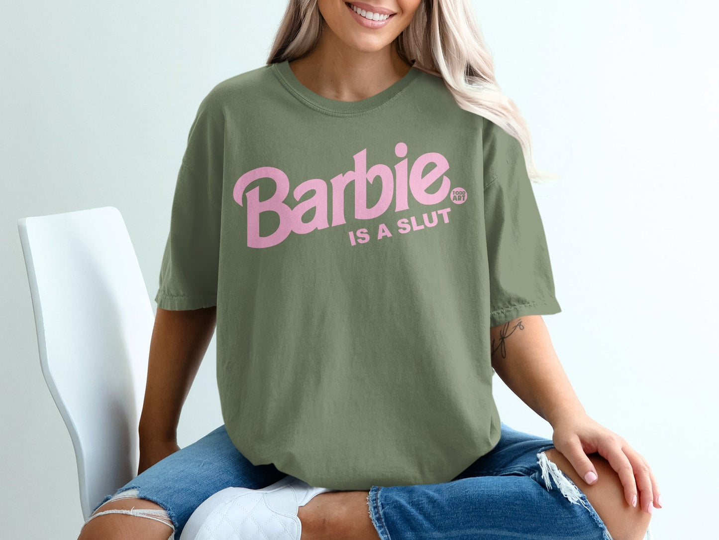 Olive green t-shirt with pink Barbie text reading "Barbie is a slut".