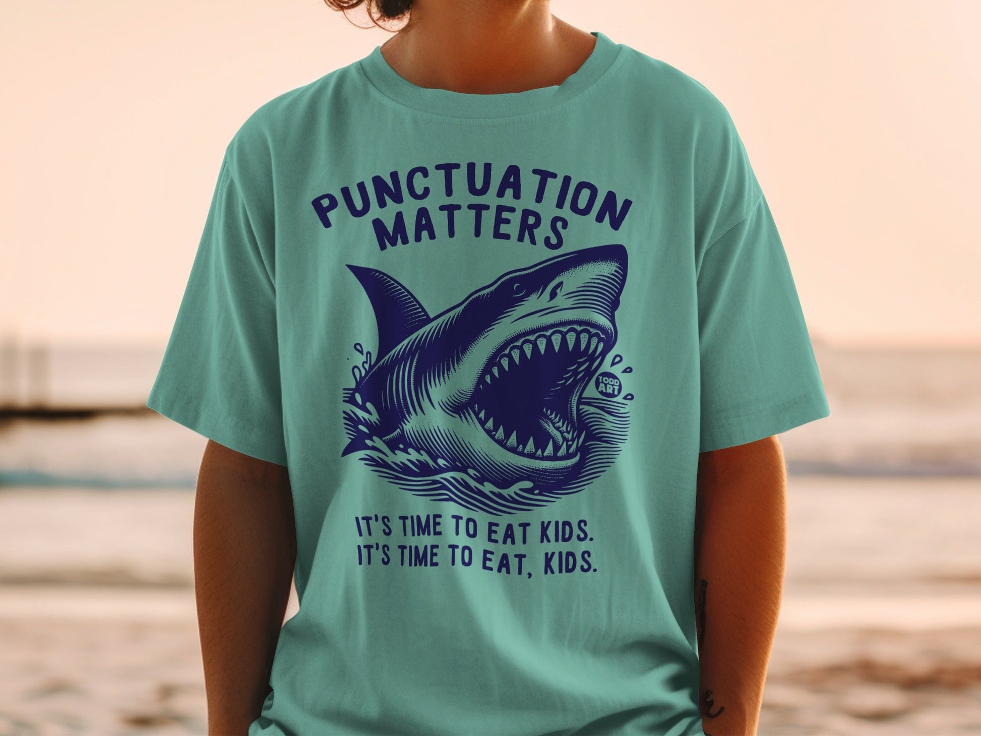 Teal t-shirt with shark graphic and "Punctuation Matters" text.