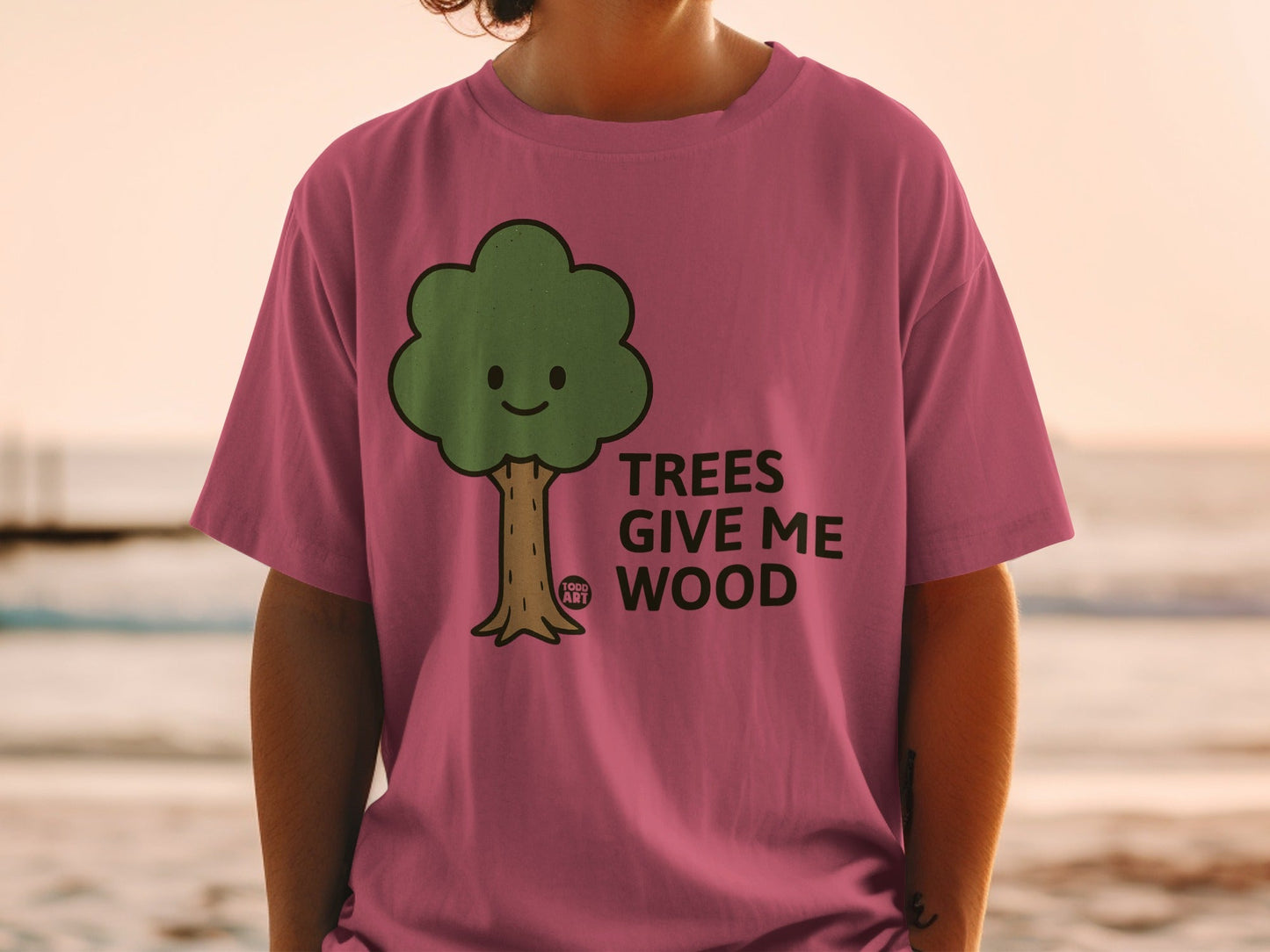 Pink t-shirt with a cartoon tree and text "TREES GIVE ME WOOD".
